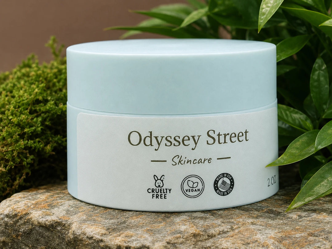 A light blue and white cosmetic jar labeled 'Odyssey Street Skincare' placed on a stone surface with green moss and leaves in the background.