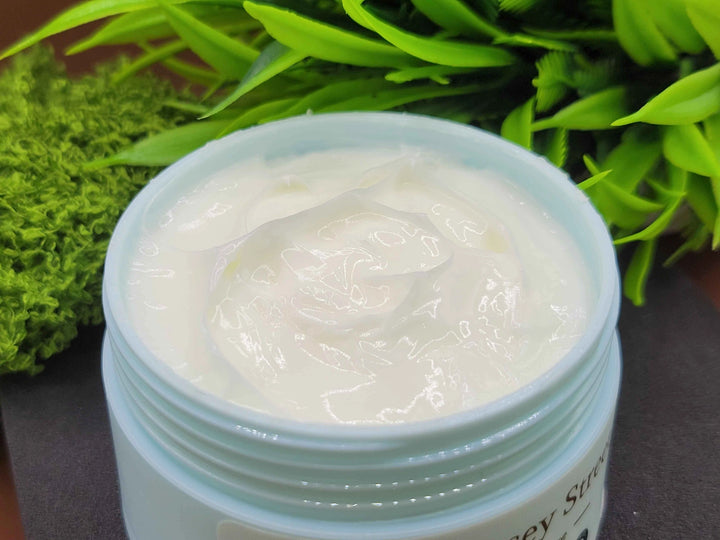 Jar of white cream with green leaves in the background